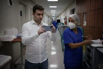 Vereador dentro de hospital filmando as dependências internas com uma enfermeira ao seu lado.