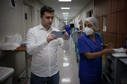 Vereador dentro de hospital filmando as dependências internas com uma enfermeira ao seu lado.