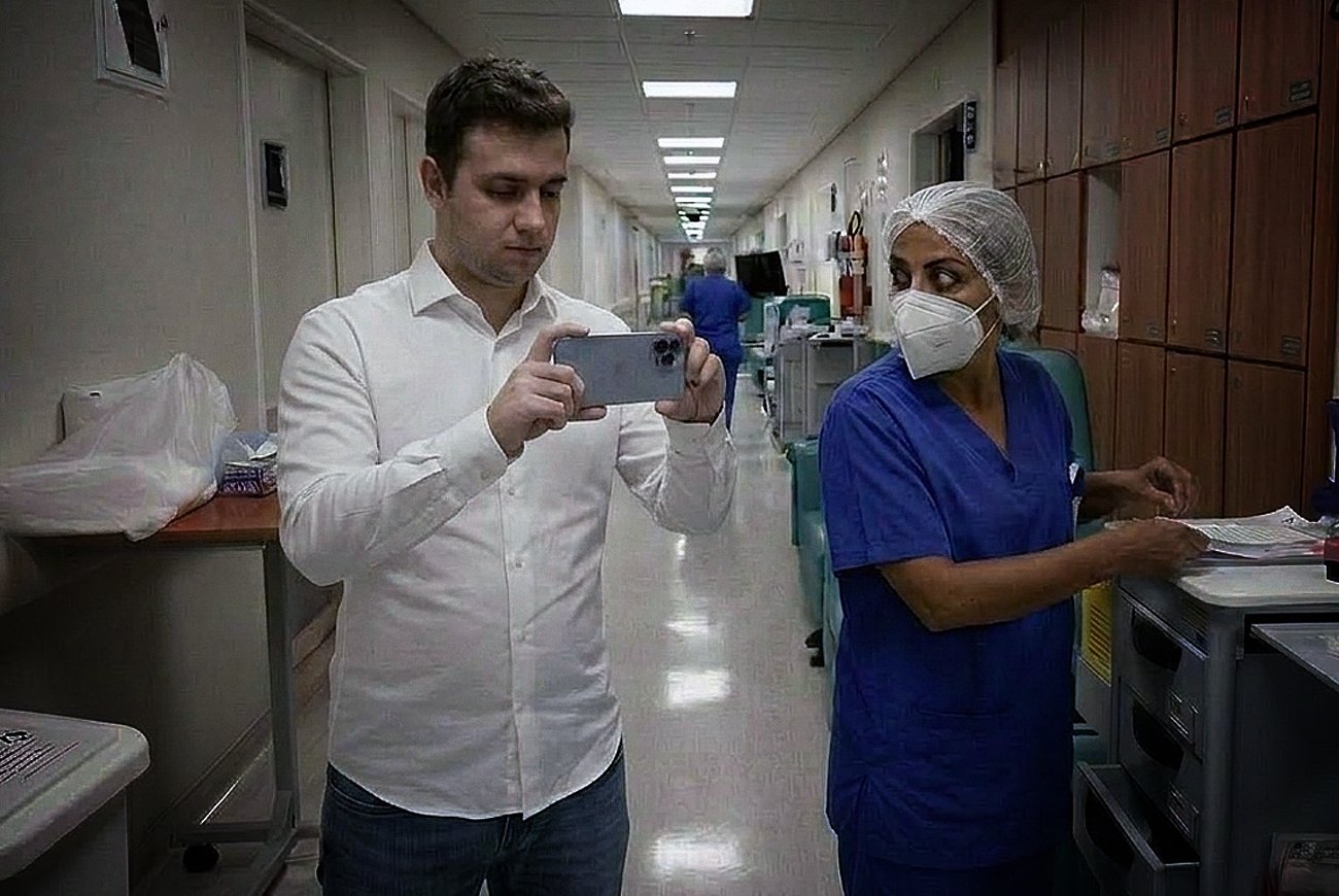 Vereador dentro de hospital filmando as dependências internas com uma enfermeira ao seu lado.