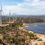 Turbinas eólicas e painéis solares no sertão do Nordeste brasileiro com linhas de transmissão ao fundo