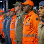 Policial militar e bombeiro em farda durante apresentação de segurança pública nas ruas