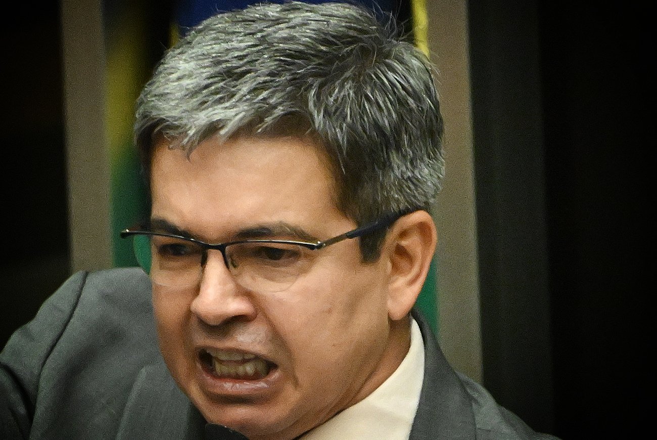 Senador Randolfe Rodrigues com bandeiras do Amapá e do Senado Federal ao fundo